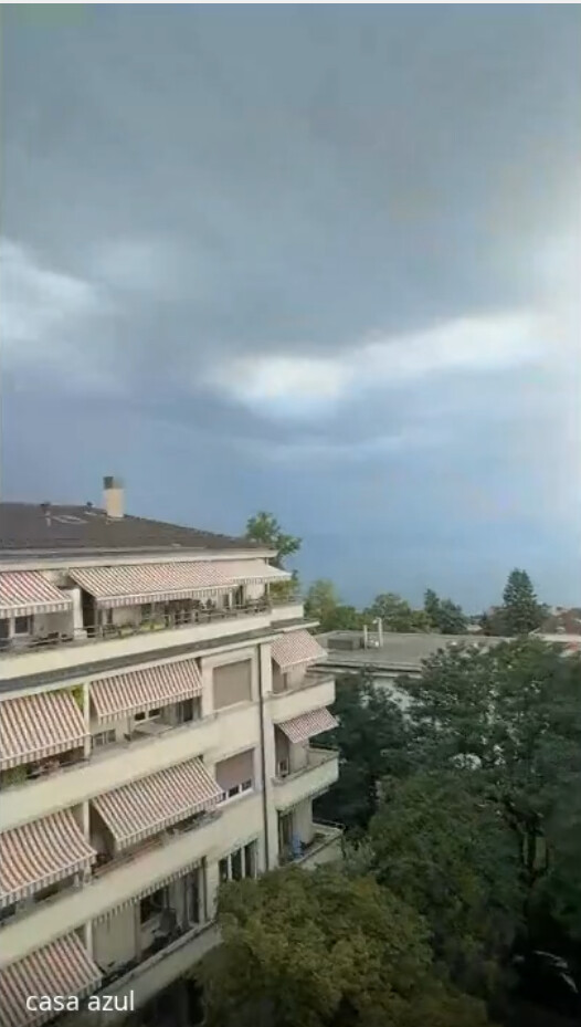 O prédio vizinho e o lago sob o céu de tempestade, visto da varanda de Fabrice