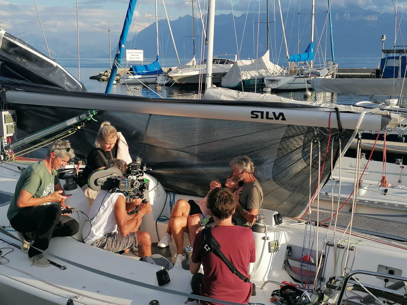 A pequena equipe trabalhando no barco atracado, as montanhas atrás